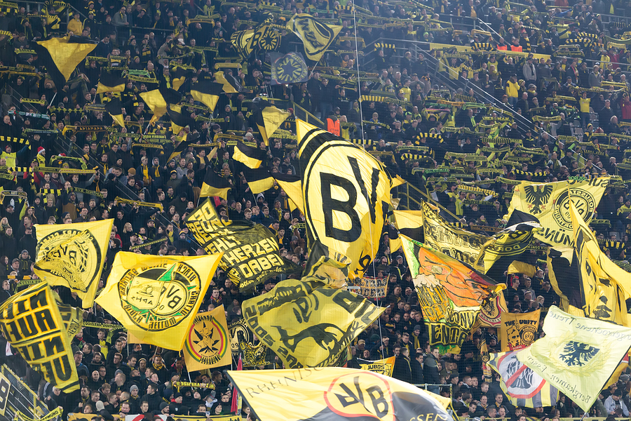 Supporters du Borussia Dortmund brandissant des drapeaux jaunes et noirs dans le stade.